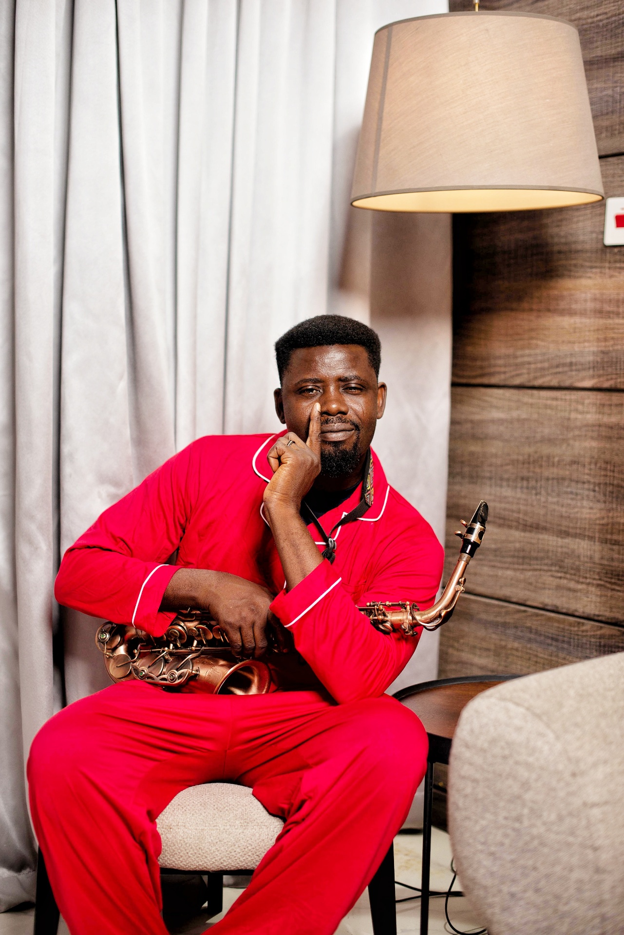 Big John Babine seated in red, holding saxophone
